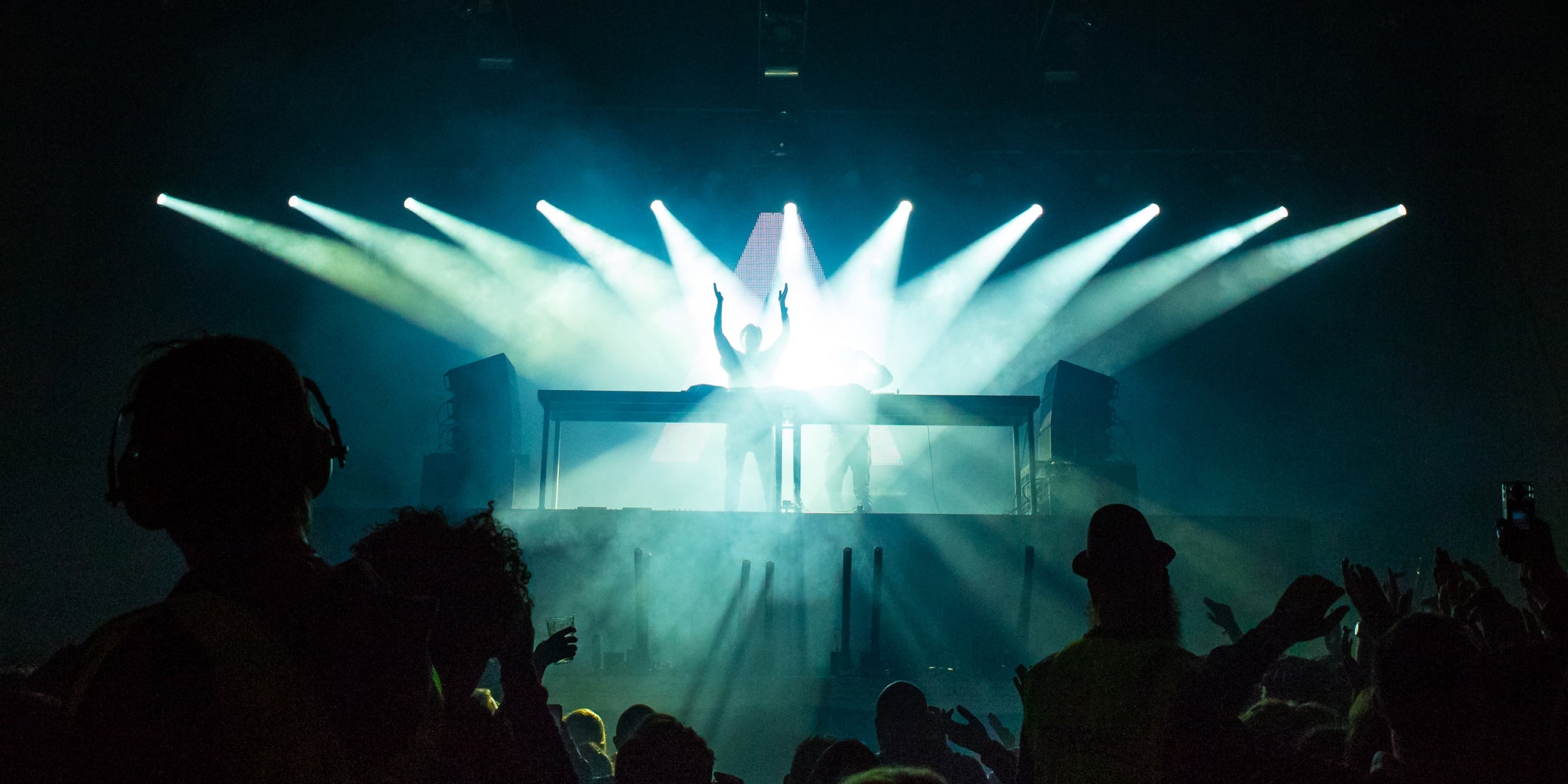 A DJ mixing at a club with a big crowd